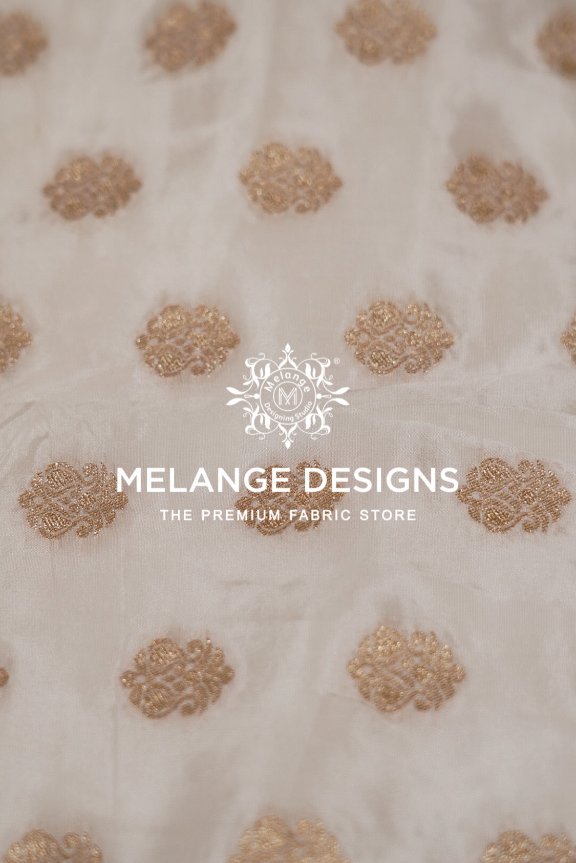 A close-up of a cream-colored Silk Brocade Dyeable Fabric  with repeating metallic gold floral motifs.
