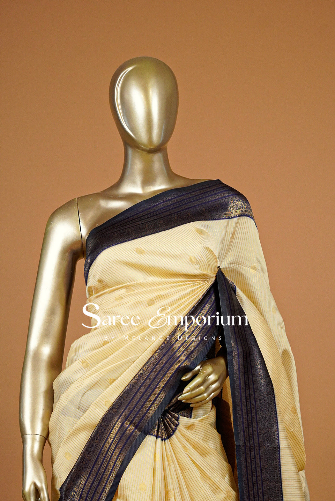 A cream-colored saree with a dark navy blue border and subtle gold motifs.
