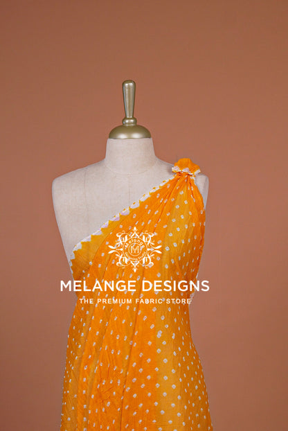 A bright yellow-orange saree with small white polka dots .