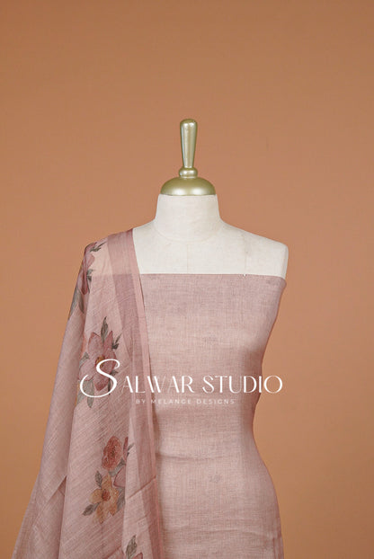 A dusty rose linen salwar suit set displayed on a white mannequin torso, featuring a solid linen tunic and a matching printed dupatta with floral motifs.