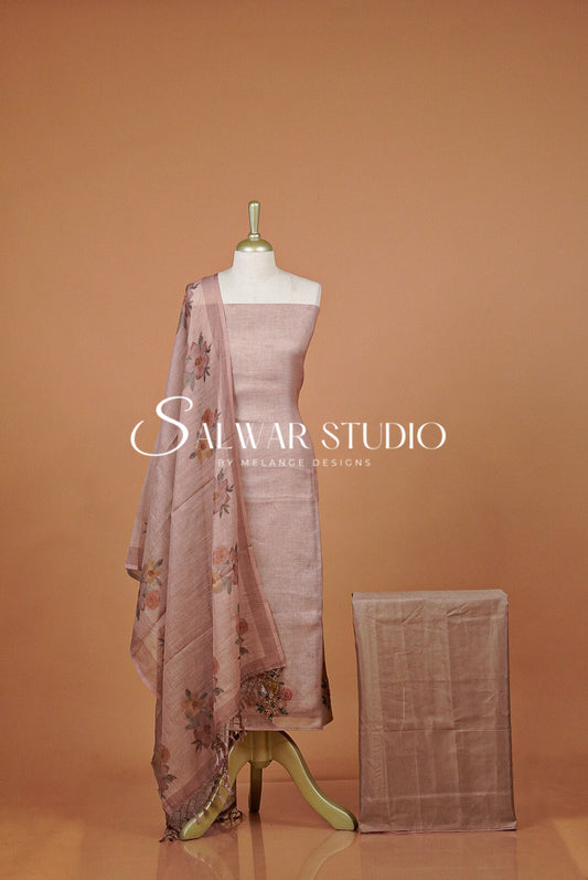 A dusty pink salwar suit set  featuring a kurta, dupatta with floral embroidery, and a matching folded fabric piece.