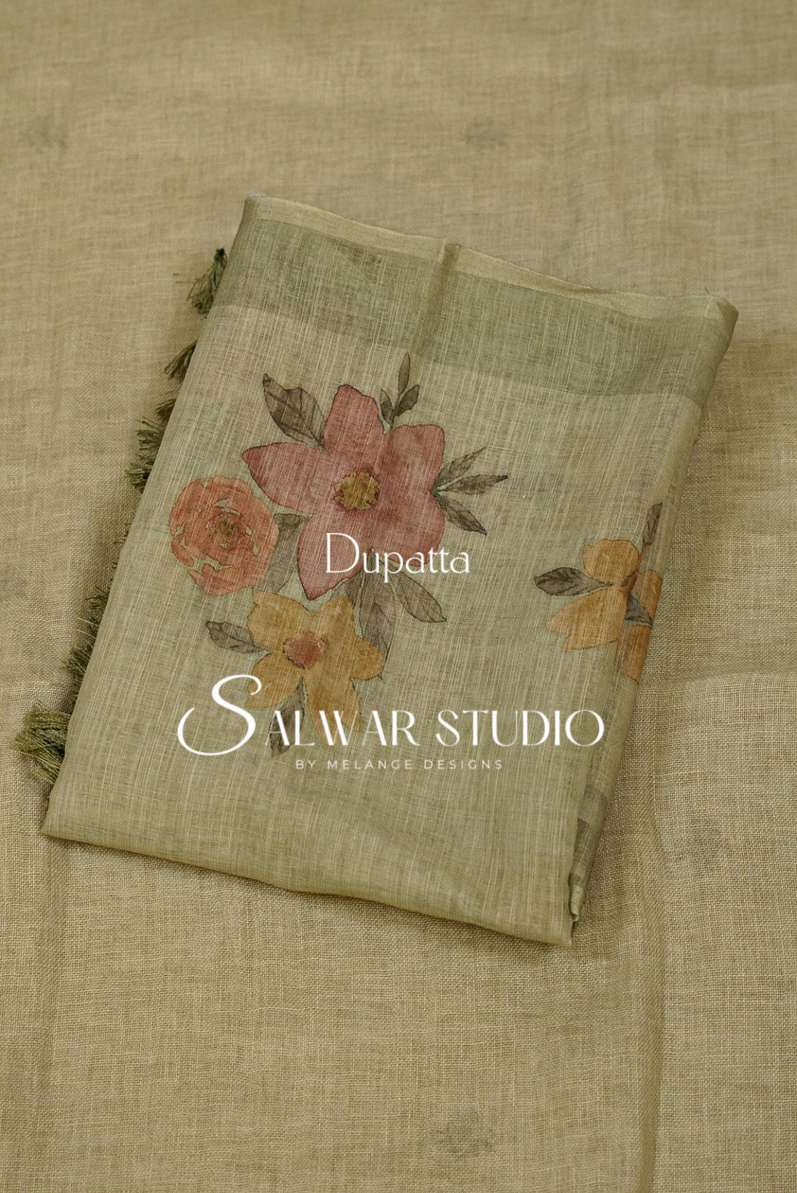 A folded dupatta made of light beige linen fabric with a floral print in muted pink, orange, and yellow tones, featuring green leaves and dark fringe on the edges. 