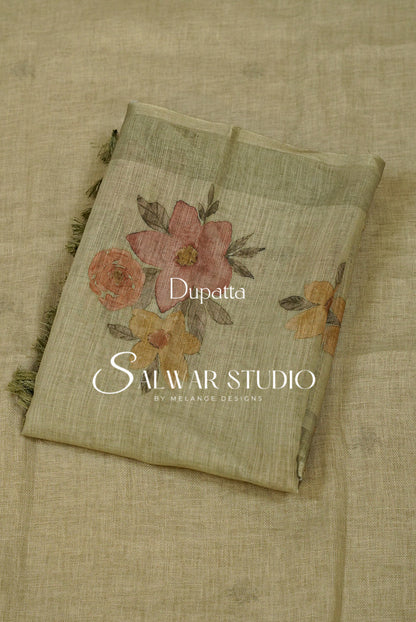 A folded dupatta made of light beige linen fabric with a floral print in muted pink, orange, and yellow tones, featuring green leaves and dark fringe on the edges. 
