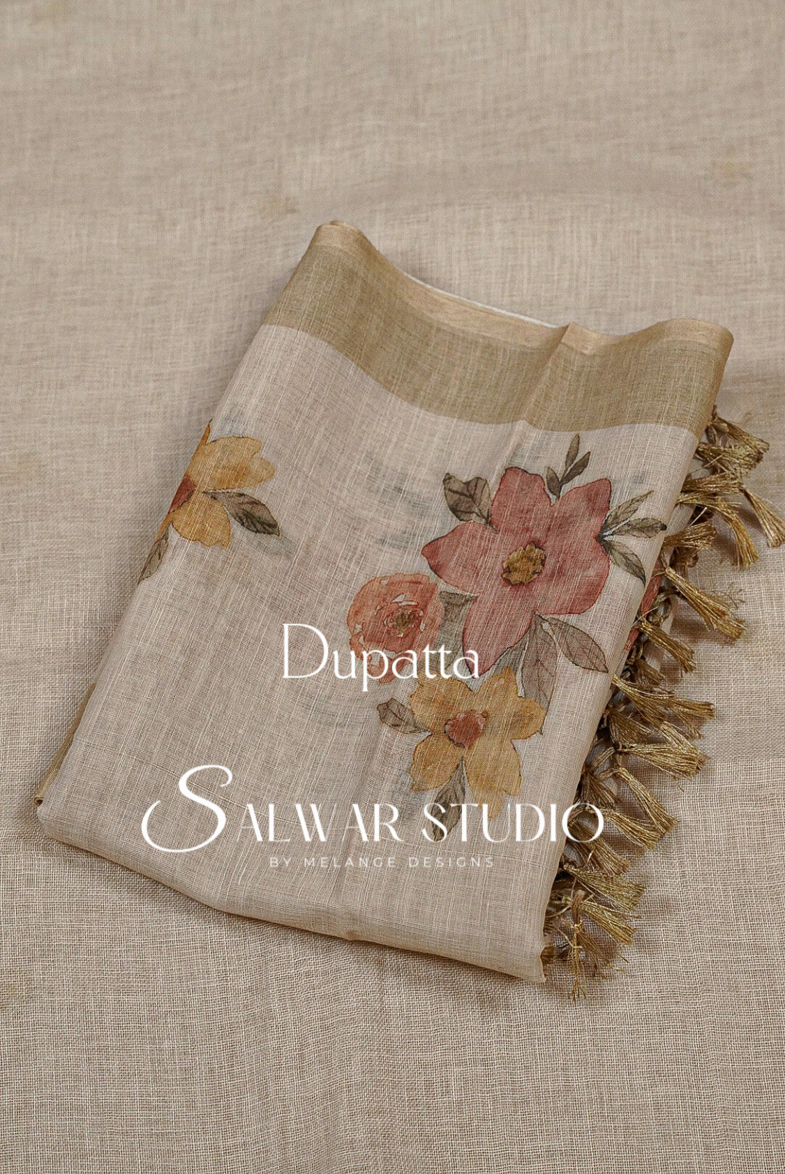 A folded dupatta with a beige linen-like base, featuring a large dusty pink and orange floral print, yellow flowers, and gold fringe.