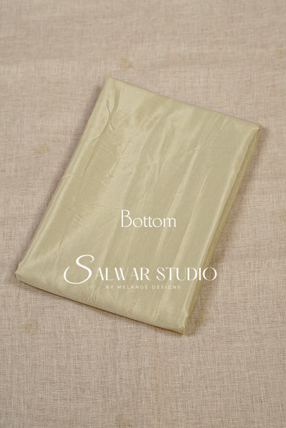 A folded light beige fabric piece, likely a bottom or lining for salwar kameez, The fabric has a subtle sheen and is folded neatly.