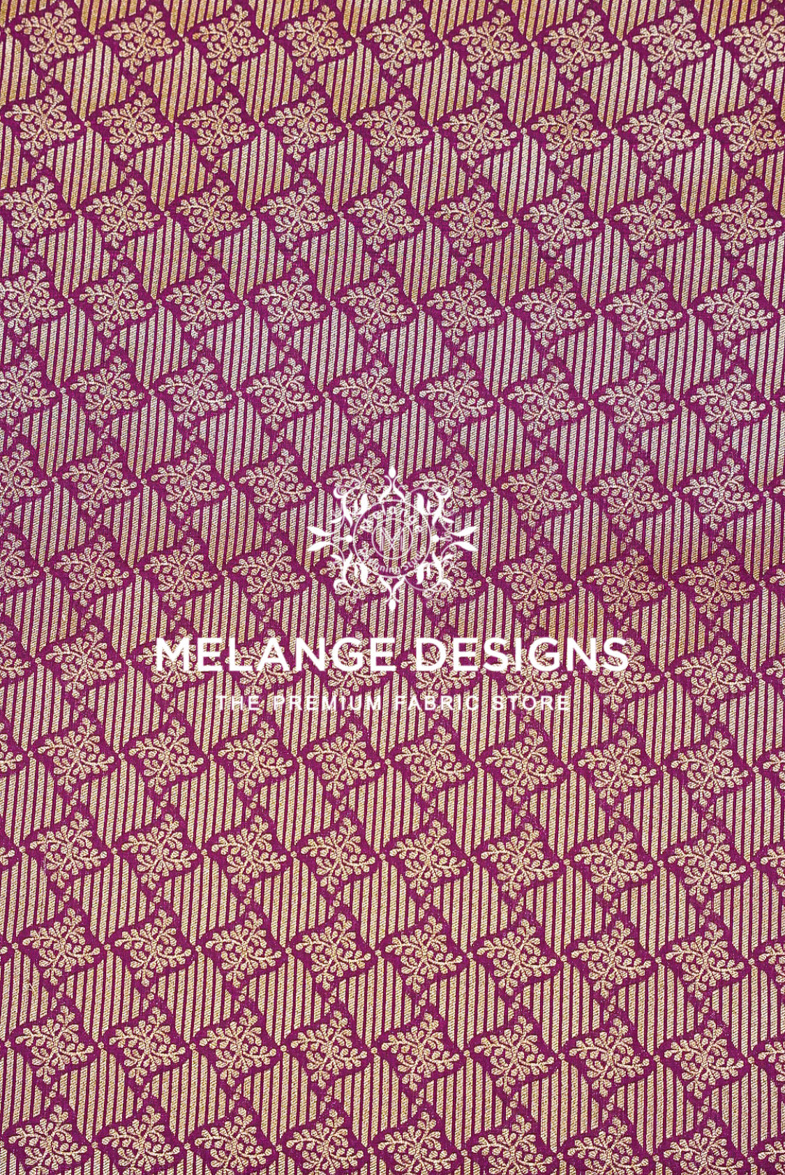 A close-up of a woven Banarasi Brocade Banarasi Brocade Fabric pattern with repeating geometric and floral motifs in magenta-purple and beige.