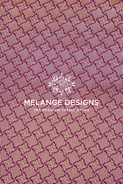 A close-up of a woven Banarasi Brocade Banarasi Brocade Fabric pattern with repeating geometric and floral motifs in magenta-purple and beige.