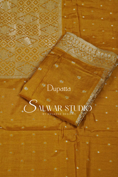 A mustard yellow salwar suit fabric  featuring a printed dupatta with a geometric pattern and a matching printed kurta fabric with small silver motifs.