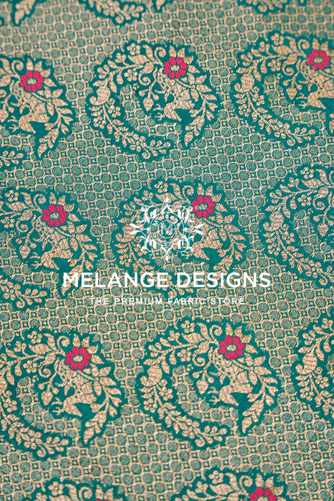 A close-up of a woven Banarasi Silk Brocade Banarasi Silk Brocade Fabric pattern featuring teal green, metallic gold, and small pink floral motifs. 