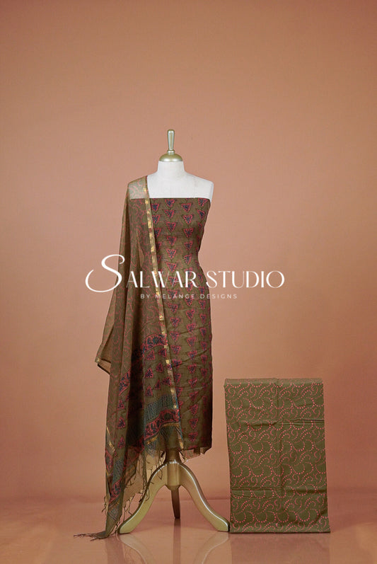 A traditional salwar suit set displayed on a mannequin and folded fabric box  The set features a brown base with intricate magenta and green floral embroidery, with a matching sheer dupatta .