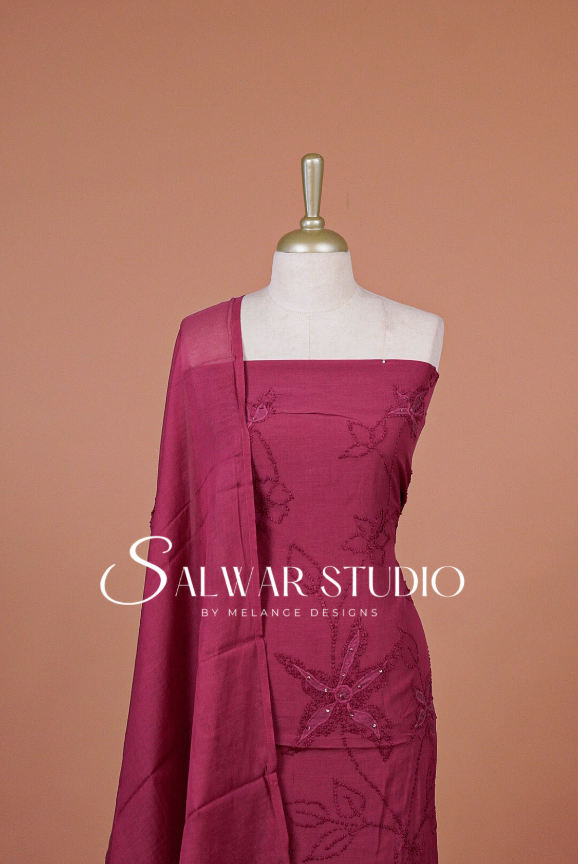 A magenta pink salwar suit set . The set includes a kurta with floral embroidery and a matching dupatta.