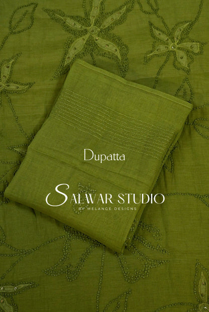An olive green dupatta with floral embroidery and stitched borders, laid flat on a matching embroidered fabric .