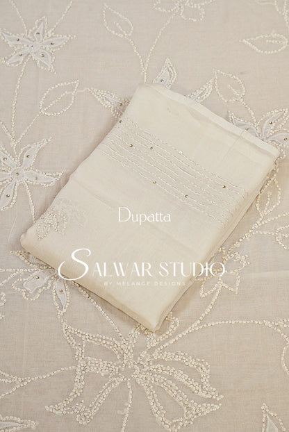 An off-white dupatta with delicate embroidery and beadwork, laid flat on a matching beige embroidered fabric. 