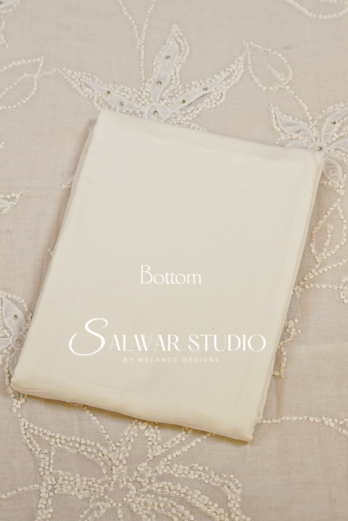 A folded cream-colored fabric garment or textile piece with printed text reading Bottom.