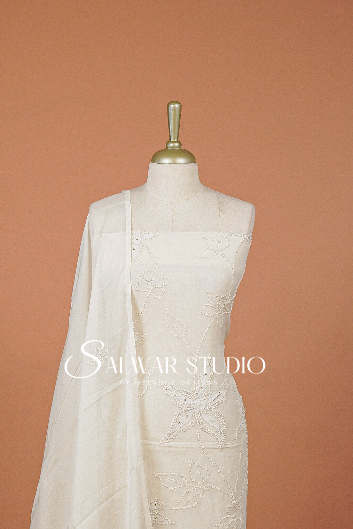 An ivory/white embroidered salwar suit set . The set includes a kurta with intricate floral embroidery, matching bottom, and a sheer dupatta draped over the shoulder.