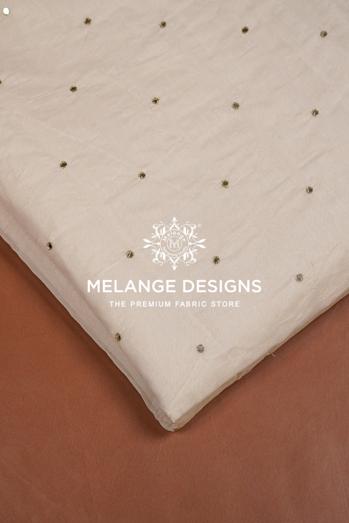 A close-up of a cream-colored Chanderi Glass Work Fabric Dyeable  with small metallic gold and silver rhinestone embellishments.