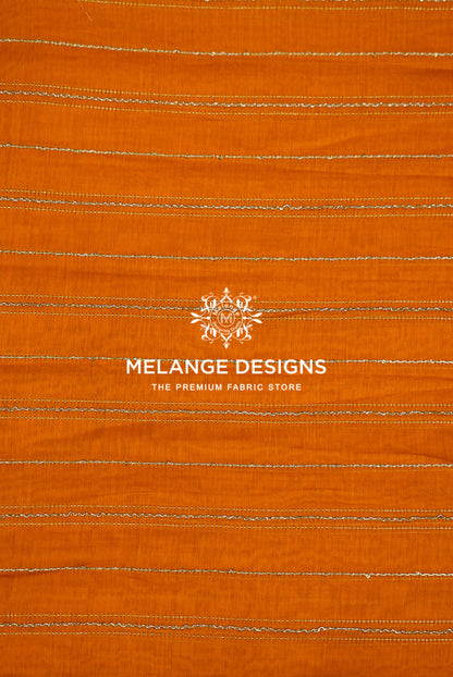 A close-up of orange Chanderi Silk Embroidery Fabric with horizontal stitched stripes .