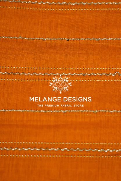 A close-up of an orange Chanderi Silk Embroidery Fabric with horizontal .