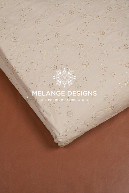 A close-up of a cream-colored Chanderi Silk Embroidery Fabric with a delicate gold floral pattern.