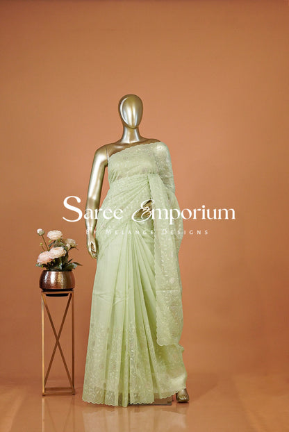 A pale mint green saree with intricate silver embroidery .