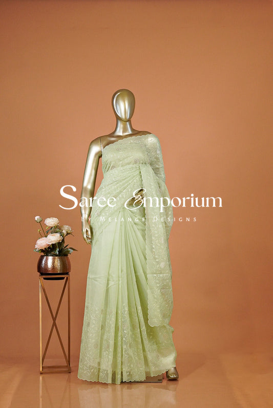 A pale mint green saree with intricate silver embroidery .