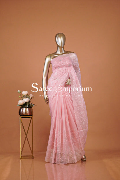A metallic gold mannequin wearing a light pink embroidered saree,