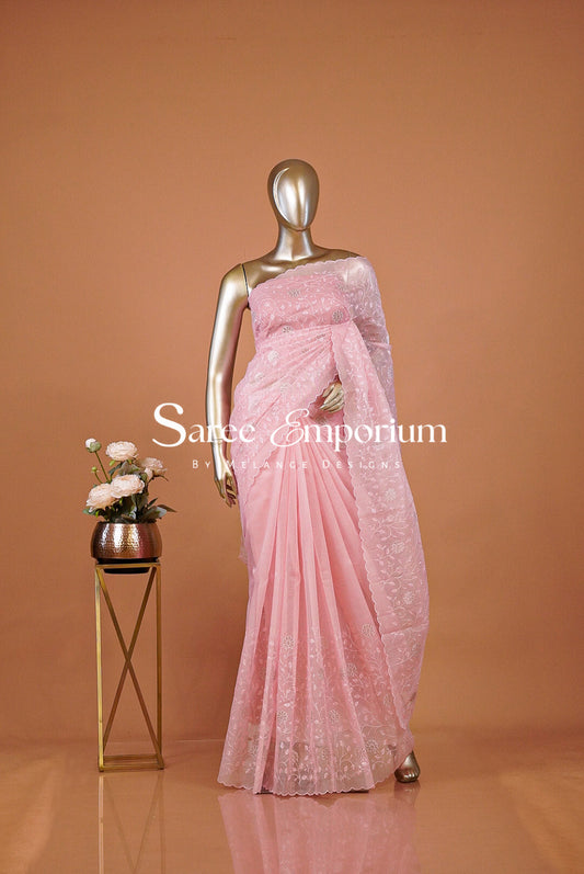 A metallic gold mannequin wearing a light pink embroidered saree,