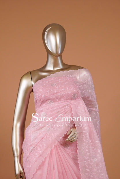 A charming Kota Embroidery Saree in a soft pastel pink shade, beautifully adorned with delicate floral embroidery across the body and pallu. The lightweight, airy texture creates an elegant drape, while the intricately embroidered scalloped border adds a graceful and feminine finish.