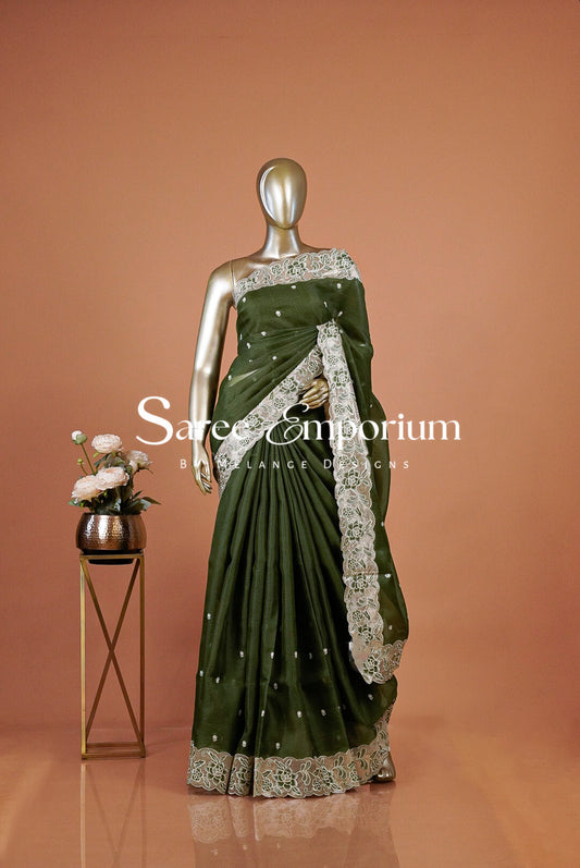 An olive green saree with intricate silver and white floral embroidery . The saree features a solid green body with detailed silver borders and small silver embellishments.