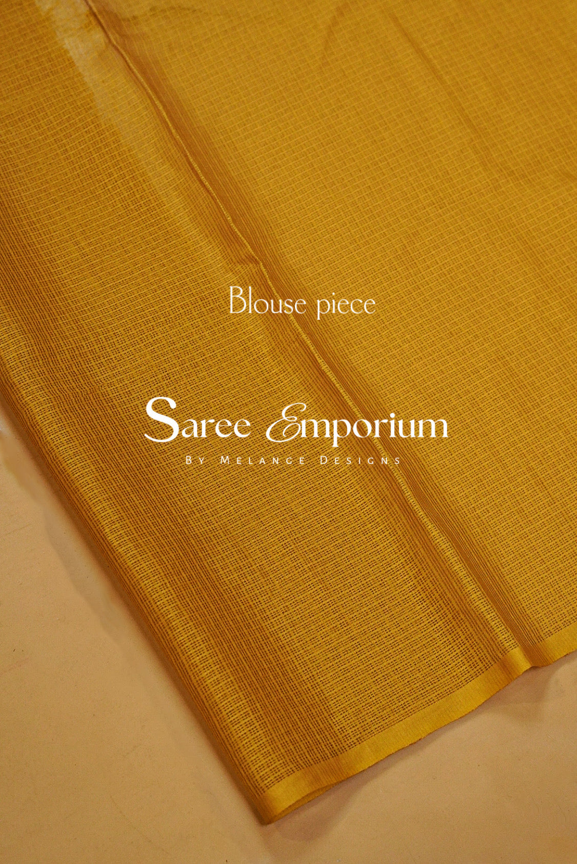 A close-up of a golden yellow saree blouse fabric with a subtle woven texture.