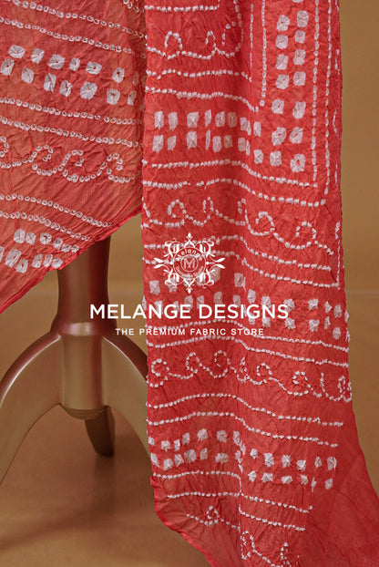 A close-up of a coral red fabric  featuring white hand-block printed patterns. 