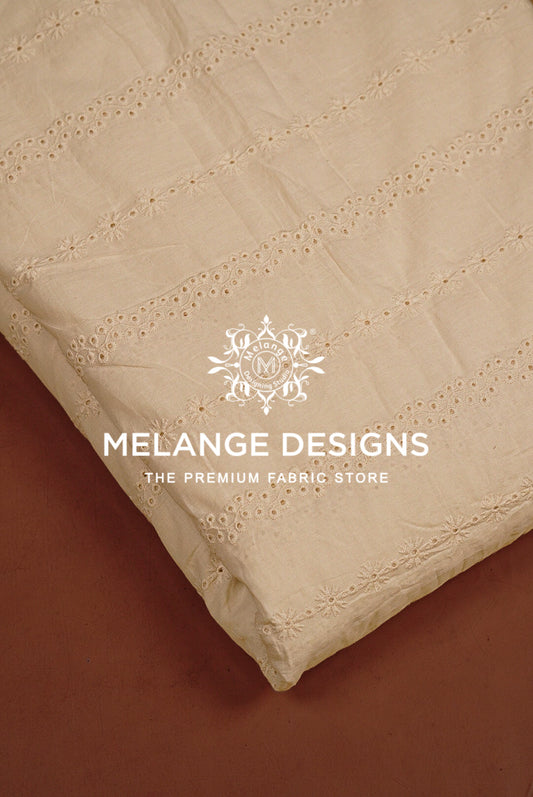 A close-up of a cream-colored Cotton Hacoba Fabric Dyeable with delicate eyelet embroidery.