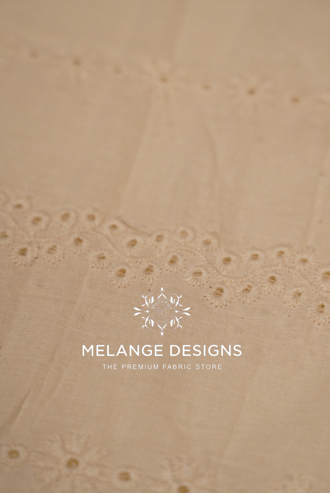 A close-up of a light beige Cotton Hacoba Fabric Dyeable with delicate eyelet embroidery .