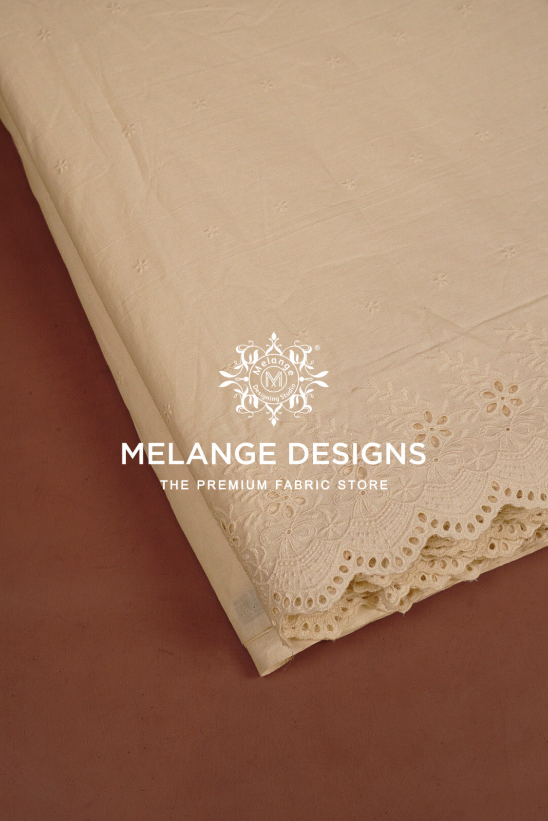 A close-up of a beige Cotton Plazzo Fabric Dyeable sample with floral embroidery and scalloped lace trim.