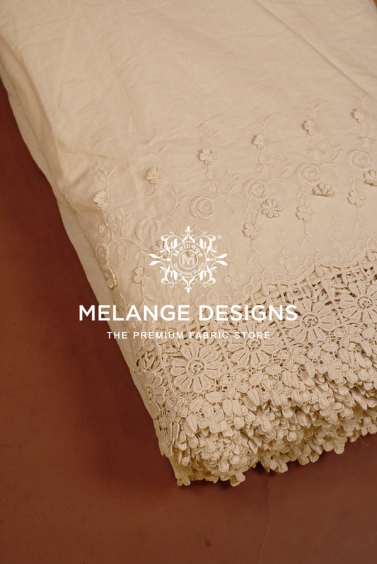 A close-up of a cream-colored Cotton Plazzo Fabric Dyeable with intricate floral embroidery and a decorative lace border.