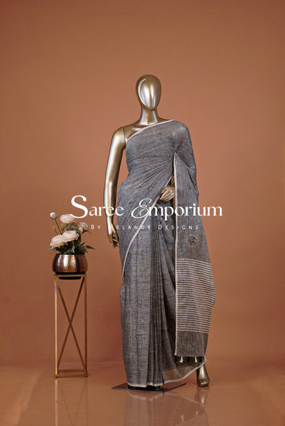 A metallic mannequin displays a draped gray saree with a striped border .