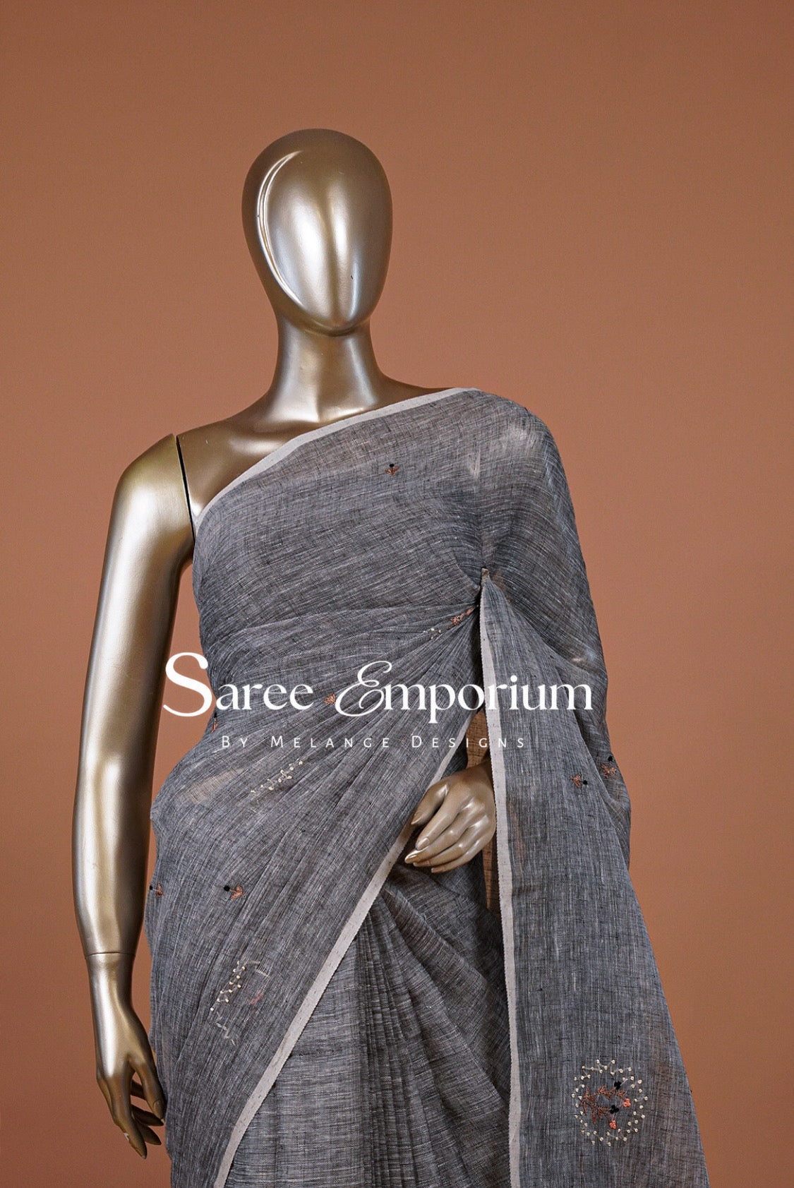 A metallic gray linen saree with white border and small red and silver embroidered motifs.