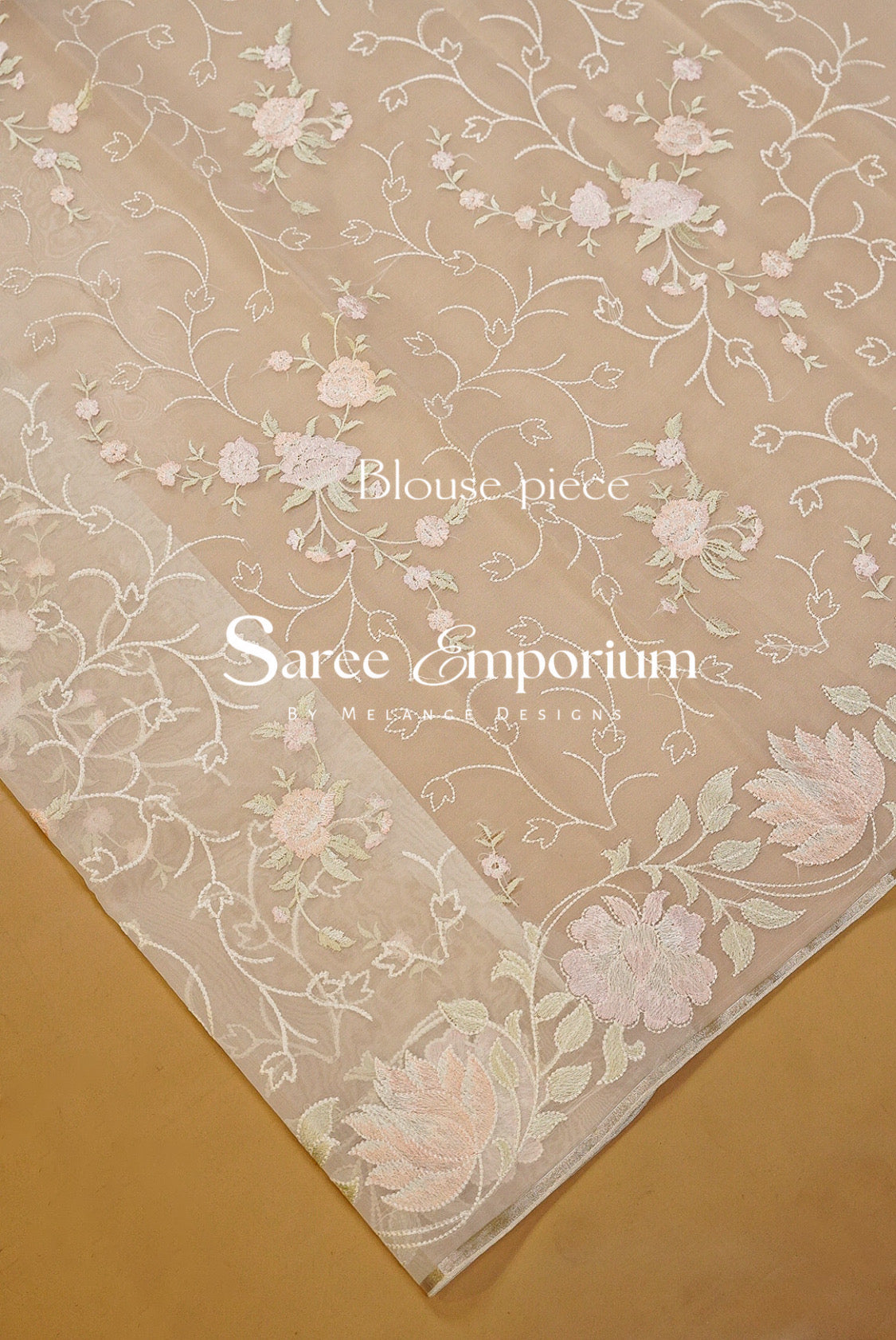 A close-up of a beige sheer fabric with delicate white floral embroidery and a matching embroidered border.