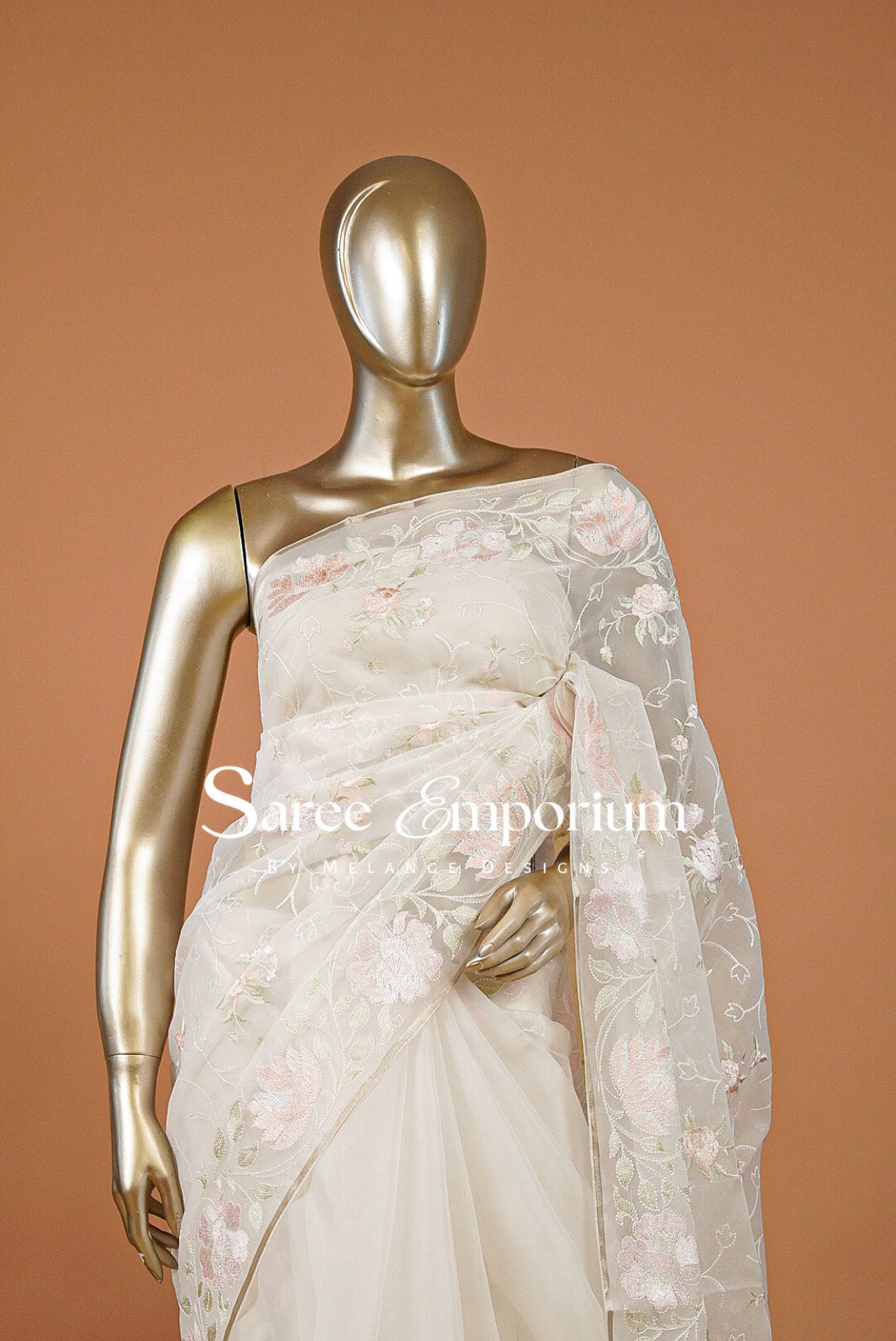 An off-shoulder ivory/cream saree with pink floral embroidery and a matching sheer dupatta.