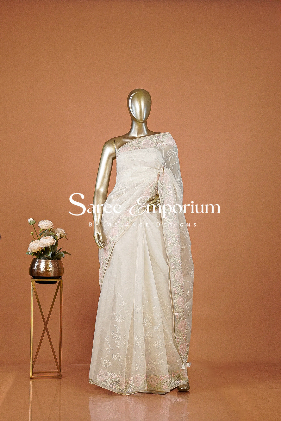 An ivory white embroidered saree .