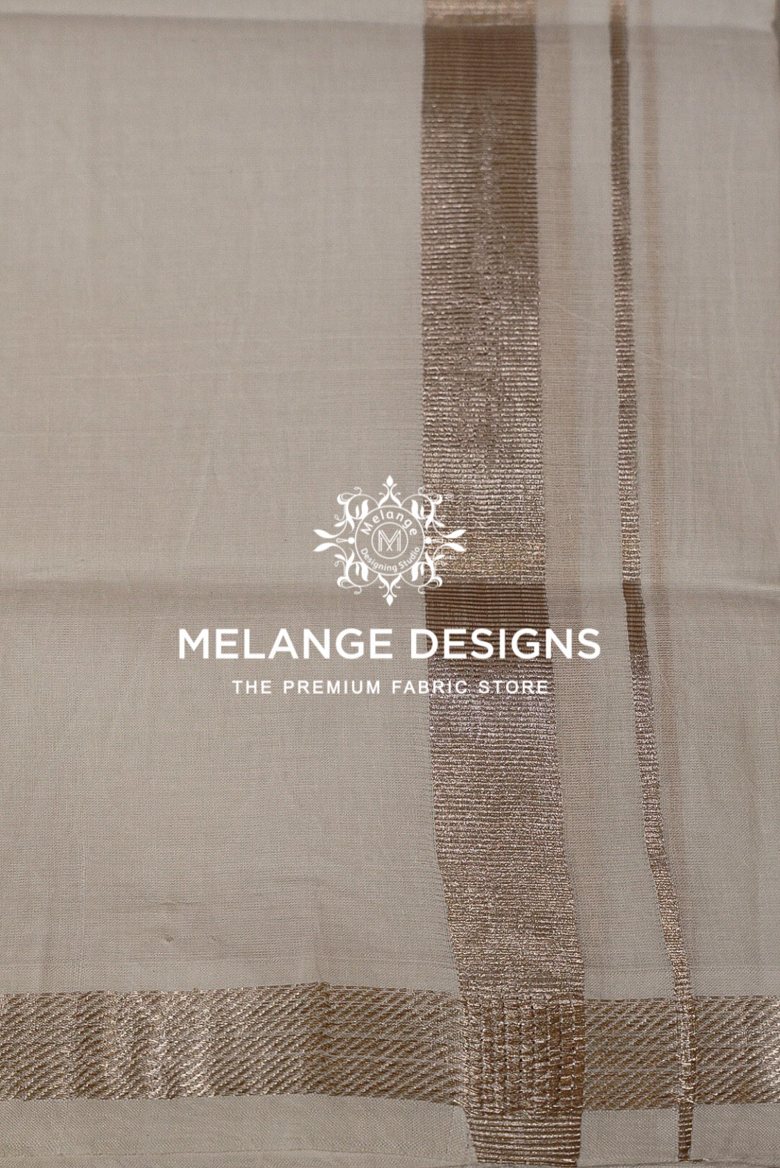A close-up of a light beige fabric with vertical metallic gold stripes and a patterned border.