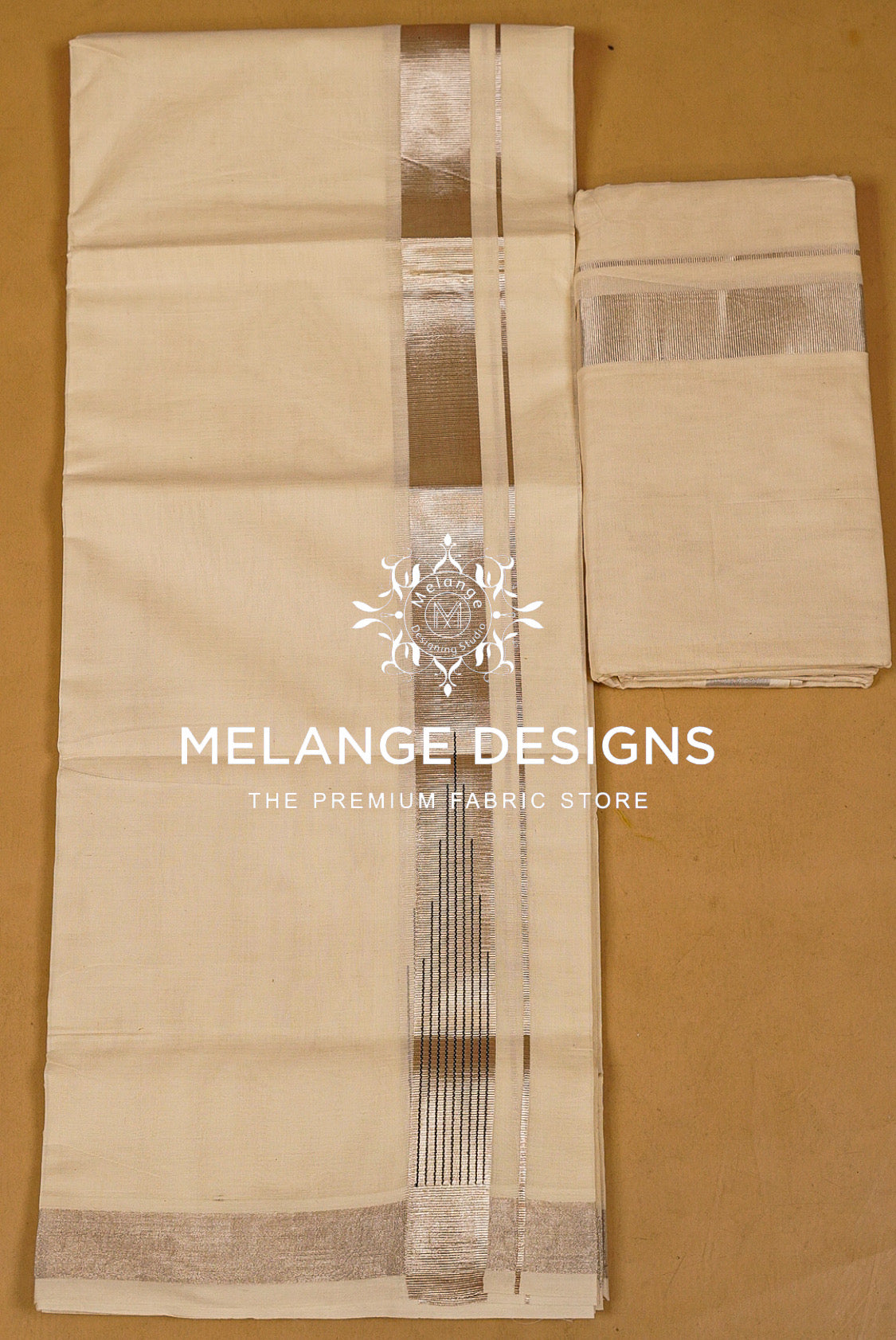 A folded cream-colored fabric saree or sari with metallic silver borders.