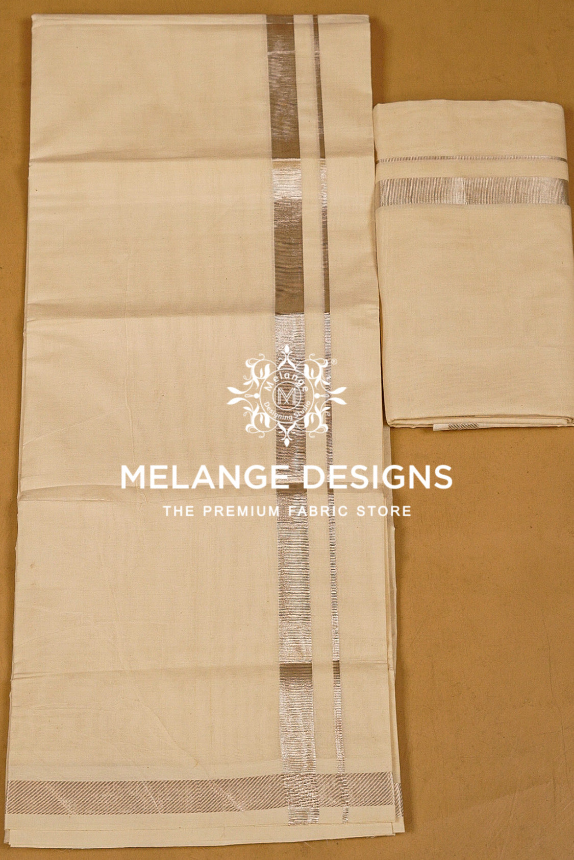 A light beige cotton dhotis featuring a central silver metallic border .