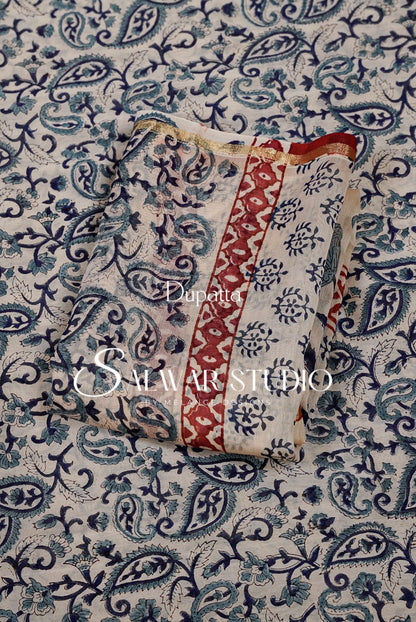 A folded piece of printed fabric with a cream base, blue paisley and floral motifs, and a red vertical border.