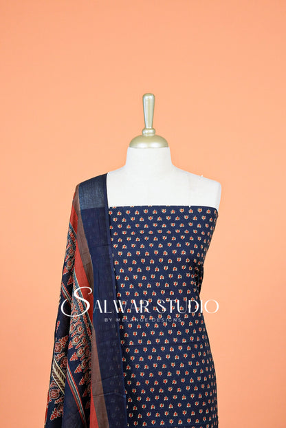 A navy blue salwar suit fabric set with small orange and beige floral prints, displayed on a white dress form A matching patterned dupatta 