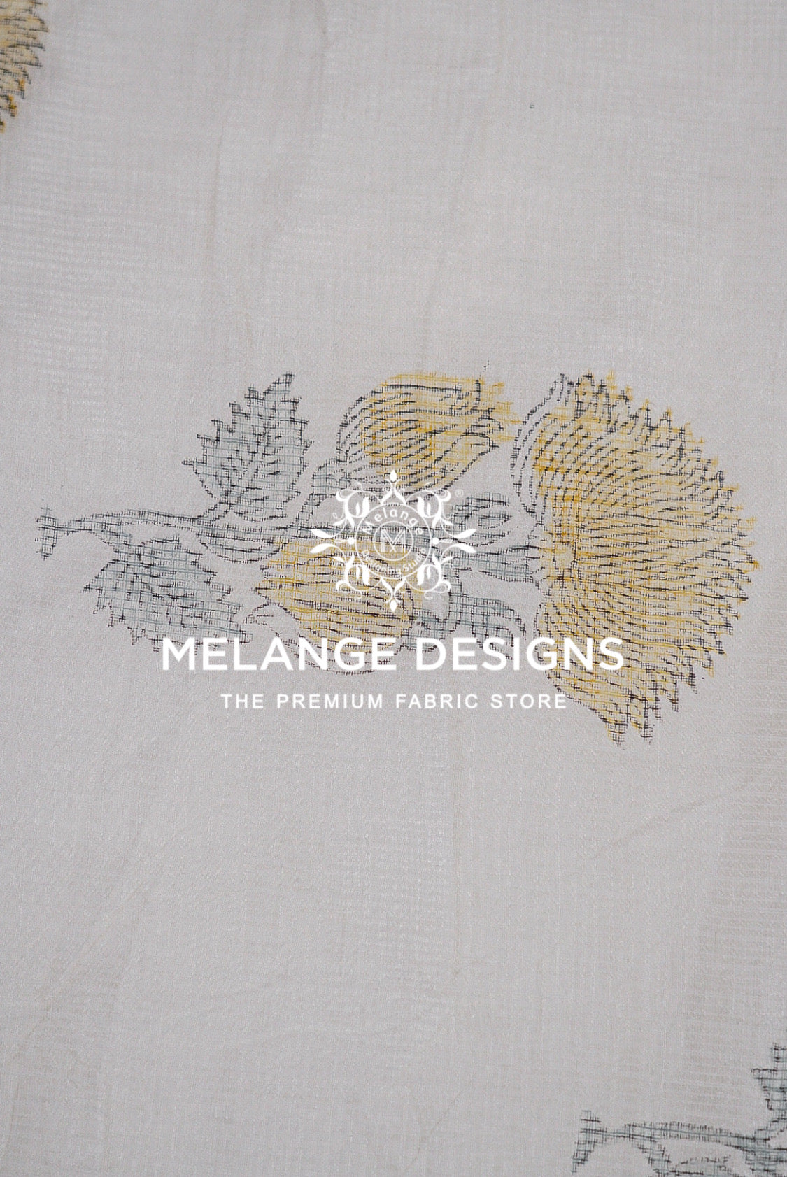 A close-up of a white Printed Cotton Cotta Fabric with a delicate embroidered floral pattern in gray and gold.