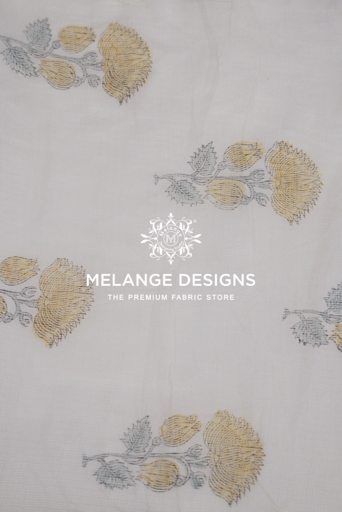 A close-up of a white Printed Cotton Cotta Fabric with a repeating block-printed floral pattern in muted gold and gray.