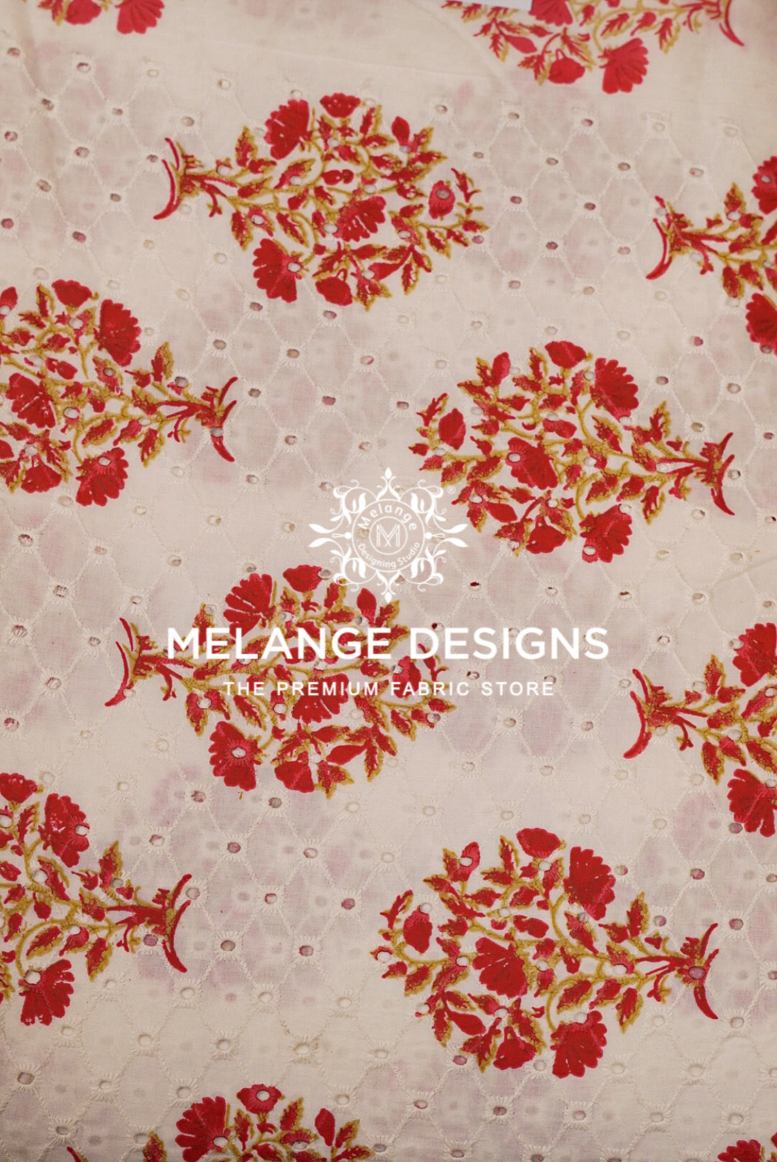A close-up of a Printed Cotton Hacoba Fabric pattern featuring red and green floral motifs over a light beige mesh background with small perforations. 