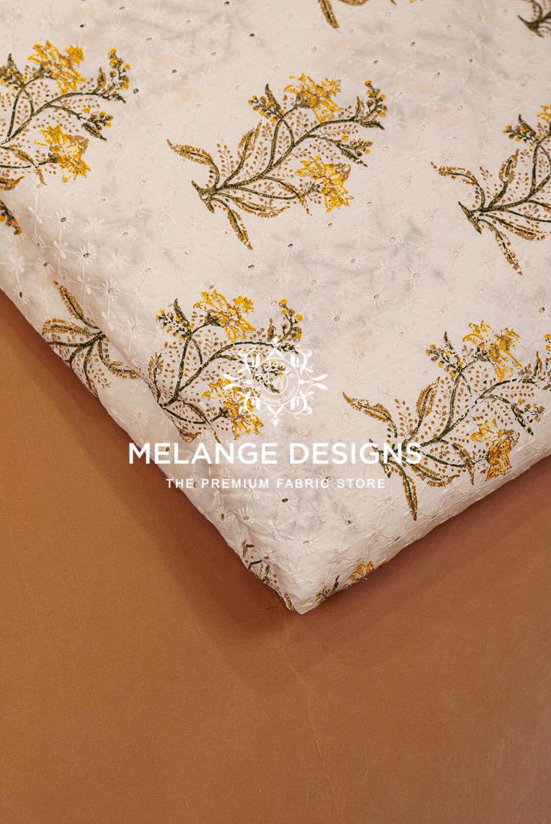 A folded piece of textured Printed Cotton Hacoba Fabric with a yellow and green floral block print on a cream .