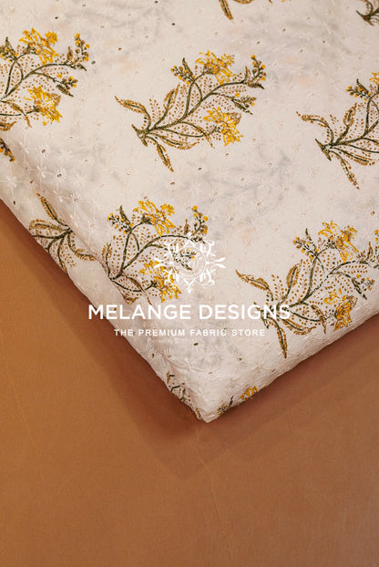 A folded piece of textured Printed Cotton Hacoba Fabric with a yellow and green floral block print on a cream .